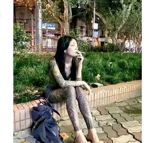  一个纹身女人坐在街边抽烟的情景,这装扮吓人一跳,手脚都是纹身