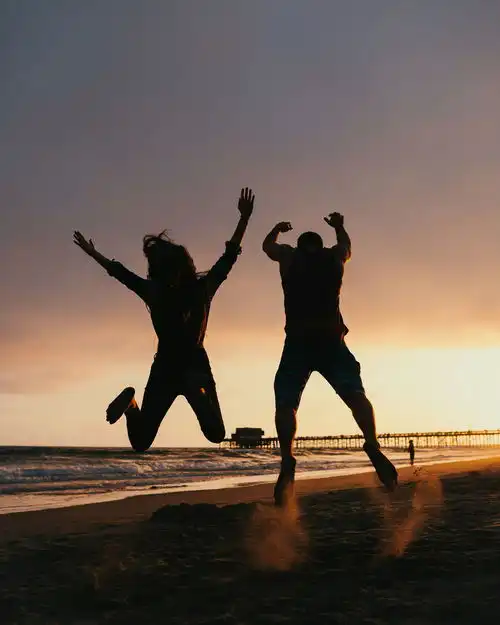  夕阳海边男女跳跃运动摄影图